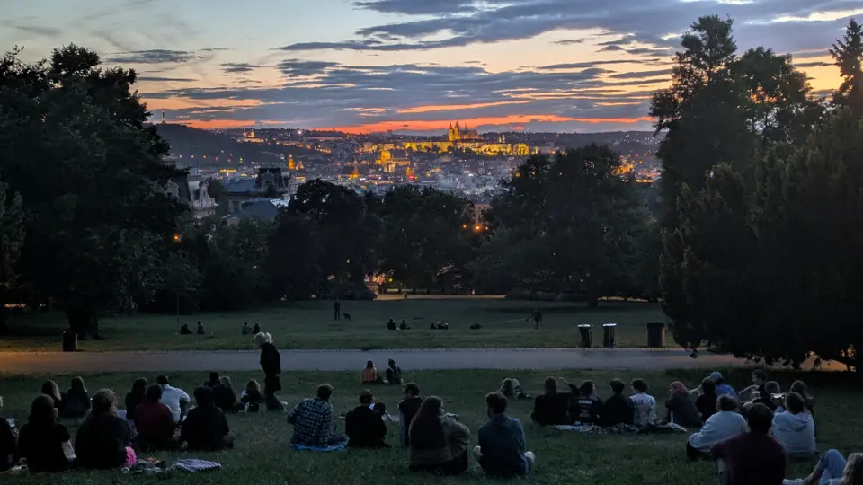 Sunset view from Riegrovy sady with people on the grass overlooking Prague Castle